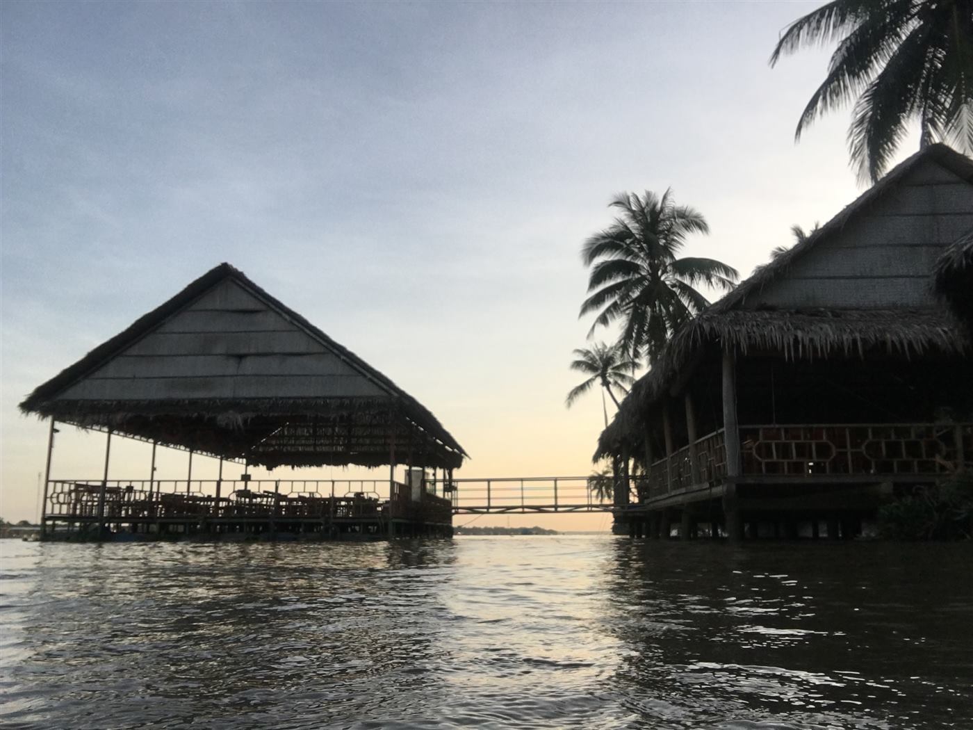 Chòi lá và cầu nối bên sông lúc hoàng hôn ở Làng Bè
